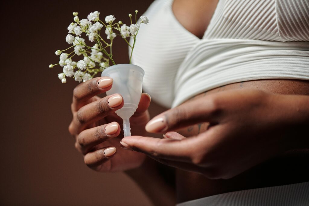 Artistic close-up of hands holding a menstrual cup with delicate white flowers, promoting feminine hygiene.